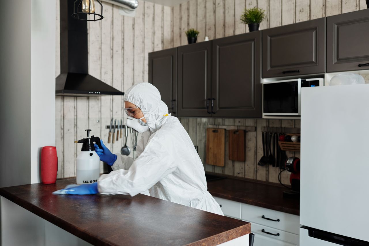 services-02 A worker dressed in protective equipment disinfects a kitchen, helping maintain a clean and safe environment.