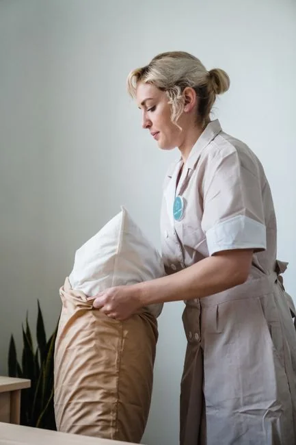 A healthcare worker wearing protective equipment disinfects a refrigerator to help maintain safety and cleanliness.